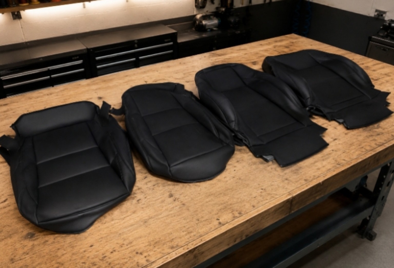 Black automotive seat upholstery pieces on a worktable